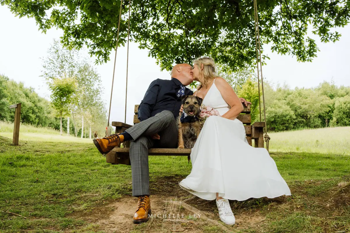 Couple who have got married on a swing seat with their dog at tree top escape